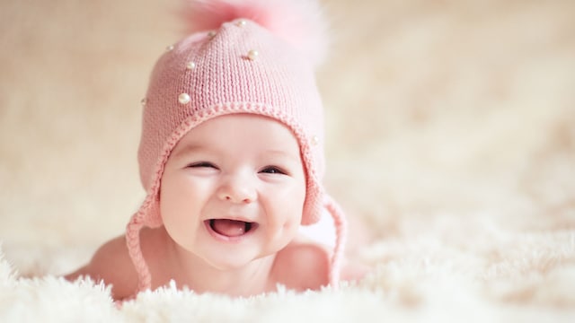 Bebé niña, con un gorrito de lana rosa, sonríe