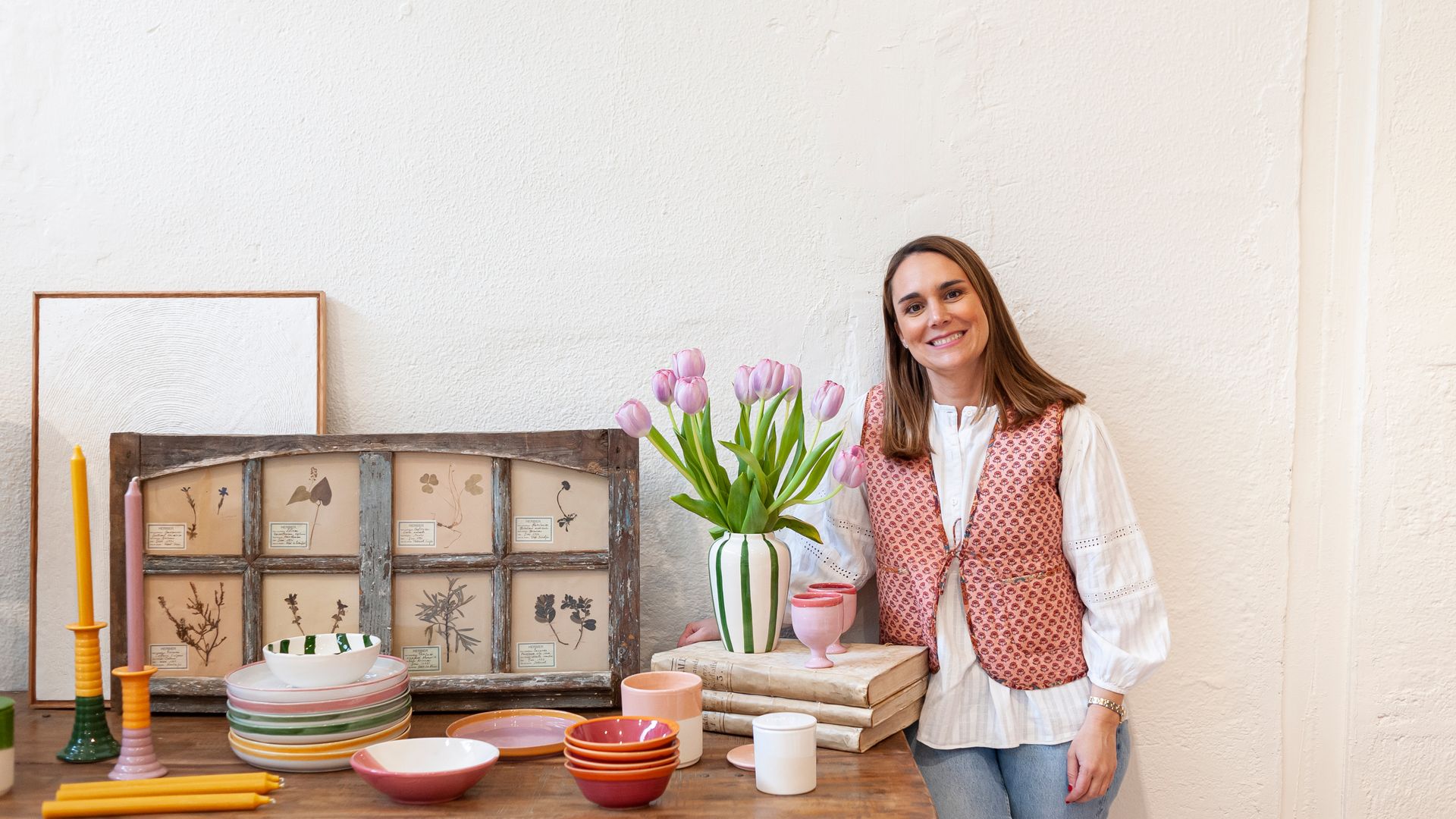 Retrato de la experta en decoración Rocío Terol con mesa con jarrón con tulipanes morados, platos de colores, candelabros, tabla decorativa
