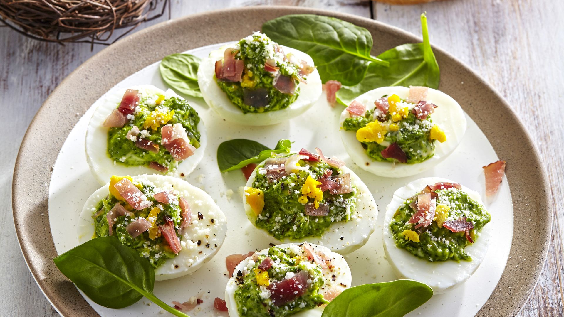 Huevos rellenos de crema verde con bacon.