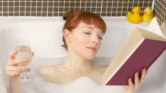 Mujer tomando un baño relajante y leyendo