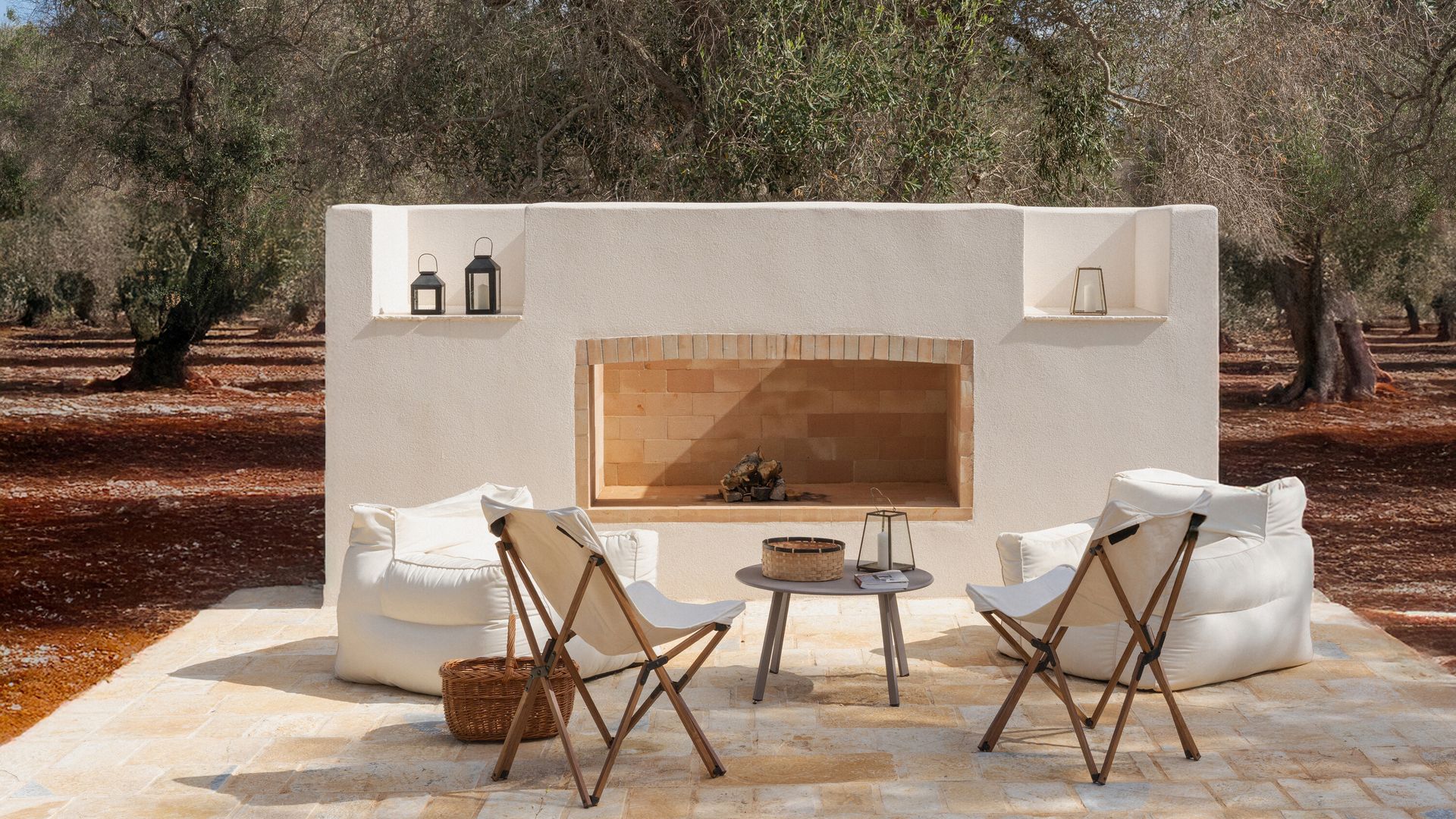 Barbacoa de obra con sillones blancos, sillas plegables y mesa auxiliar 