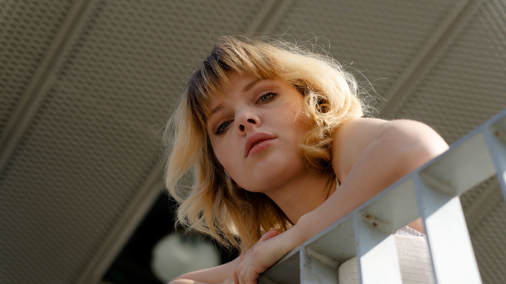 Mujer rubia con flequillo mirando por el balcón 