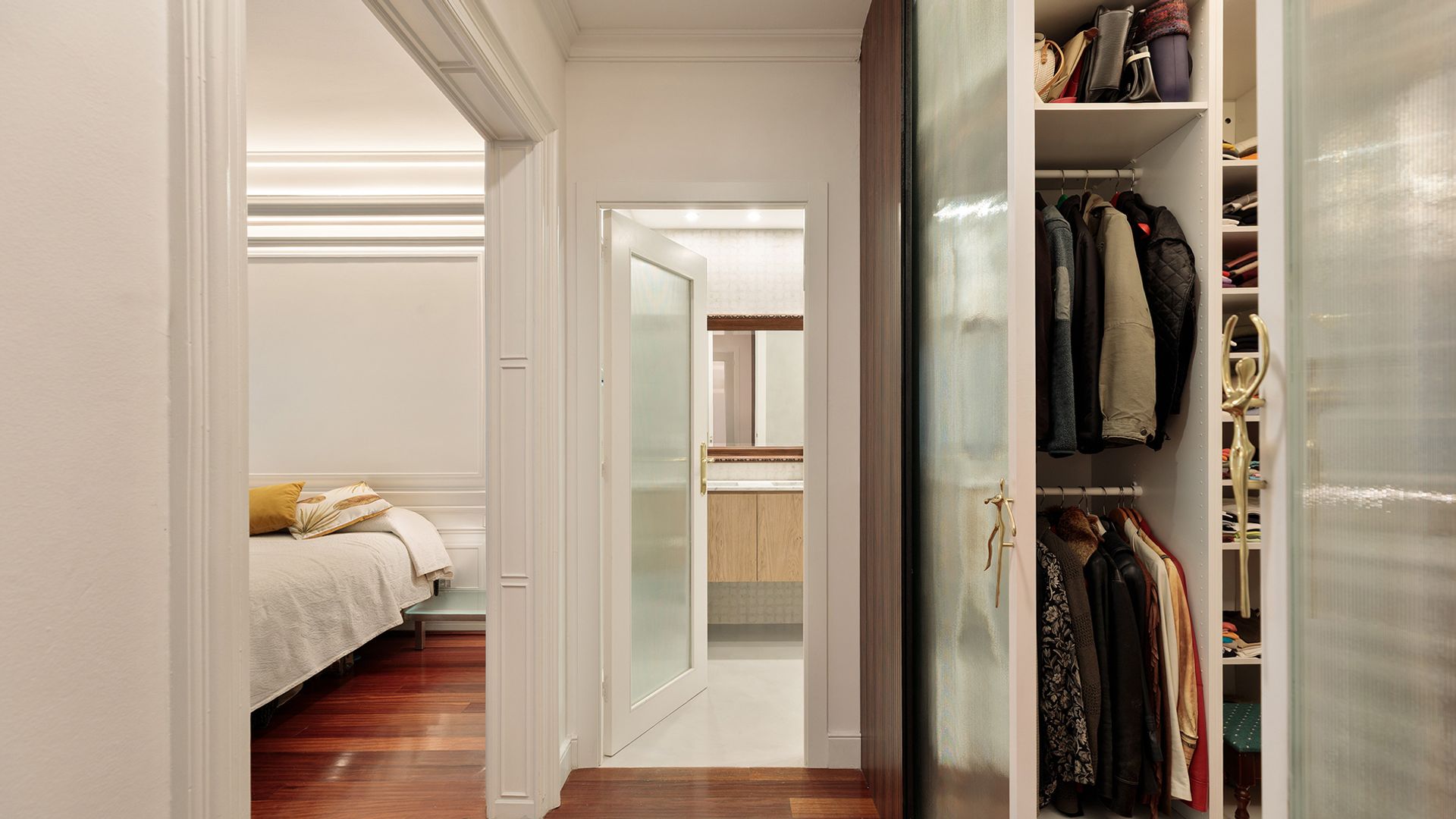 Dormitorio con baño y vestidor, suelo de madera, puertas blancas, puertas de cristal translúcido 