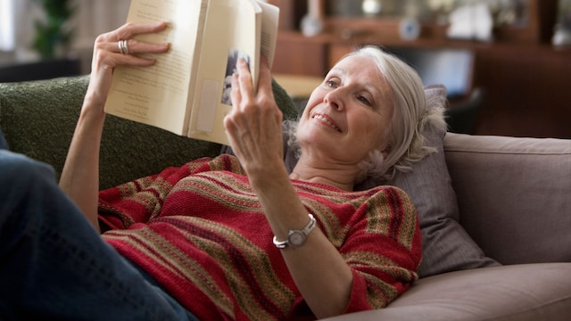 mujer madura relajada leyendo en un sofá