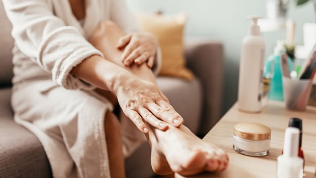 mujer aplicando crema en sus piernas