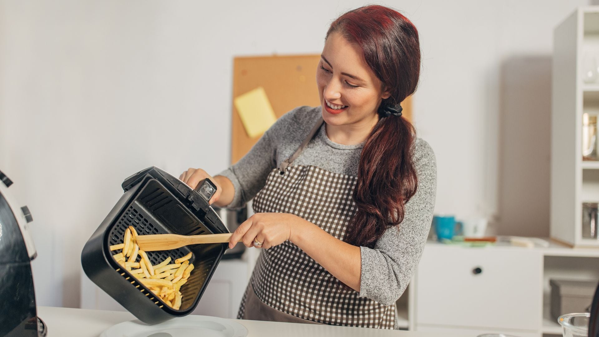 Una chica friendo patatas en una airfryer
