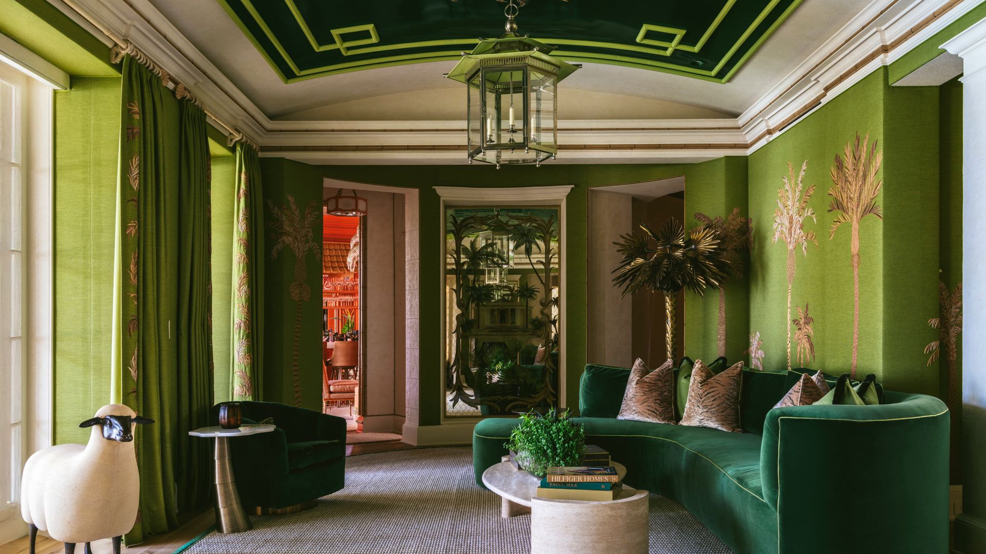 Sala en tonos verdes con amplio sofá, mesa, y estatua de oveja