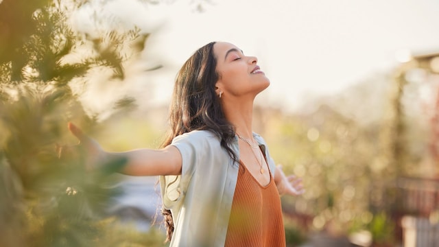 Mujer respirando al aire libre con los brazos abiertos