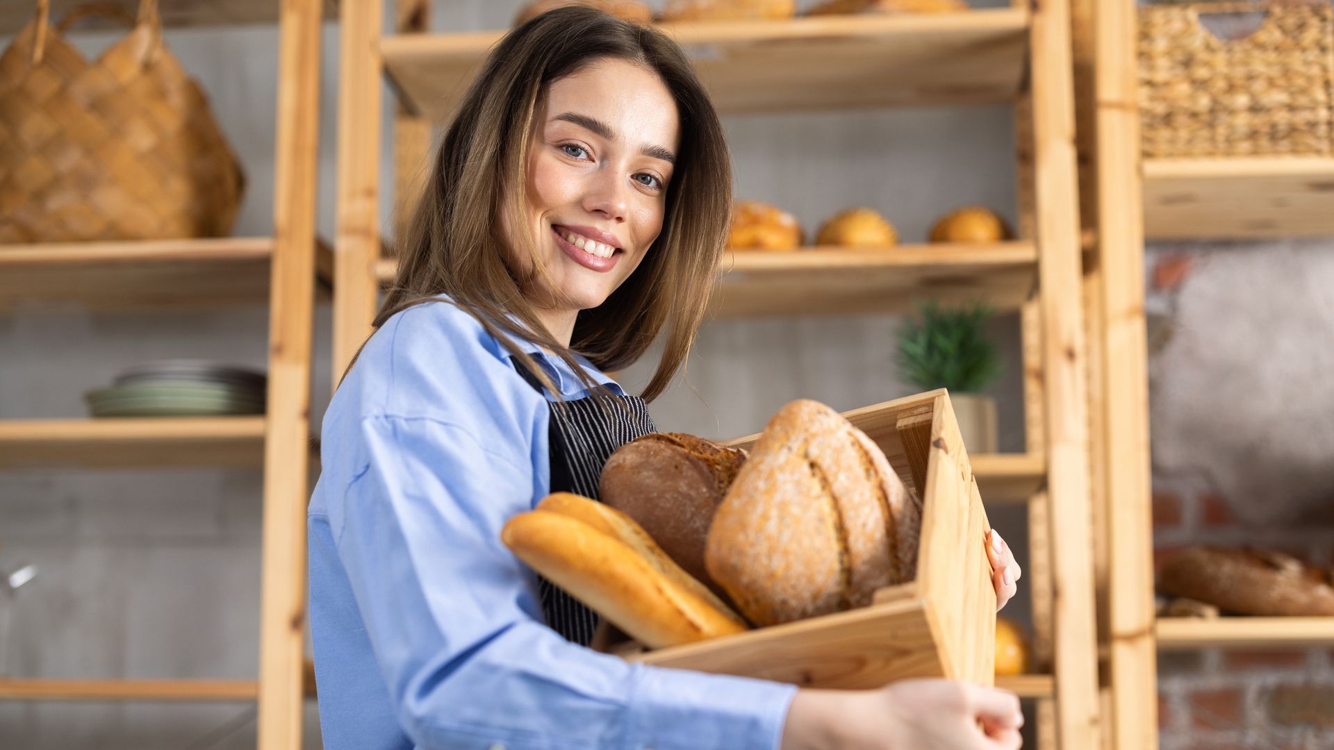 Una chica en la panadería con una caja y varias barras de pan