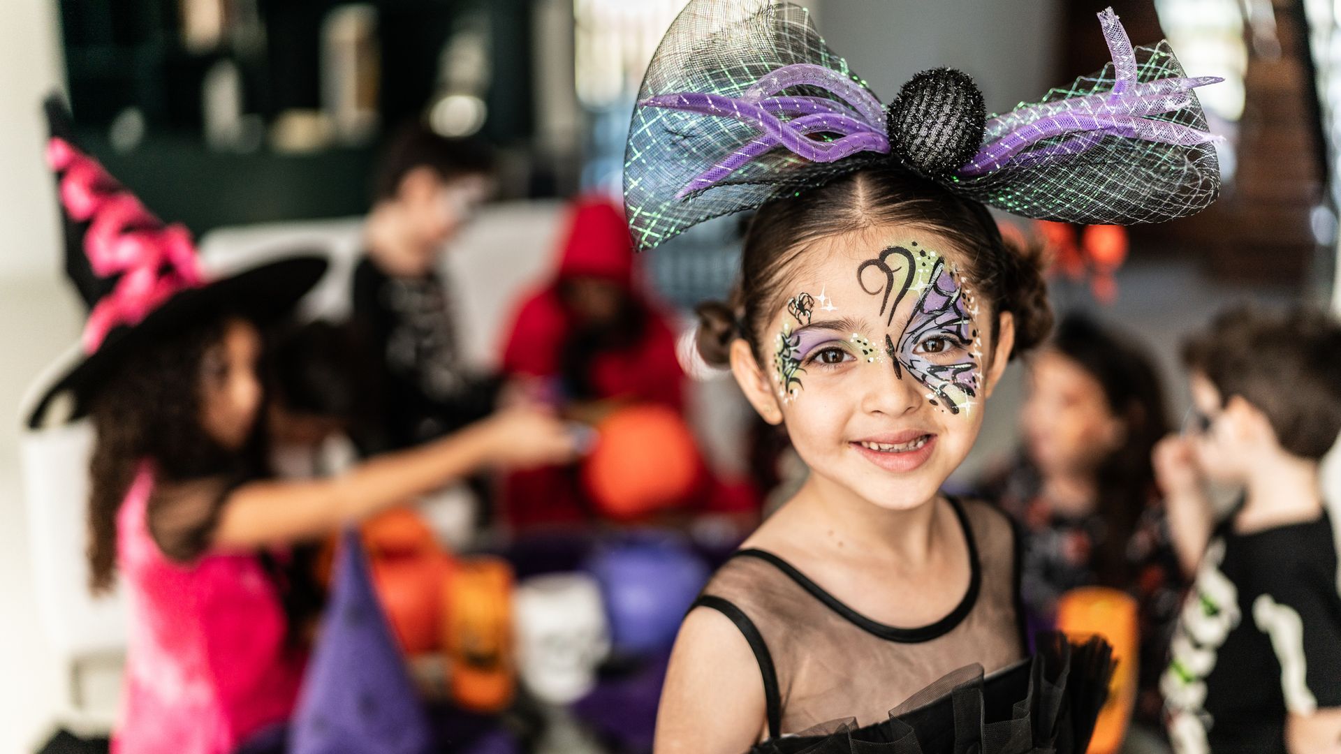 Maquillaje niños Halloween. Fiesta en casa con una niña en primer plano disfrazada y maquillada en morado y verde.