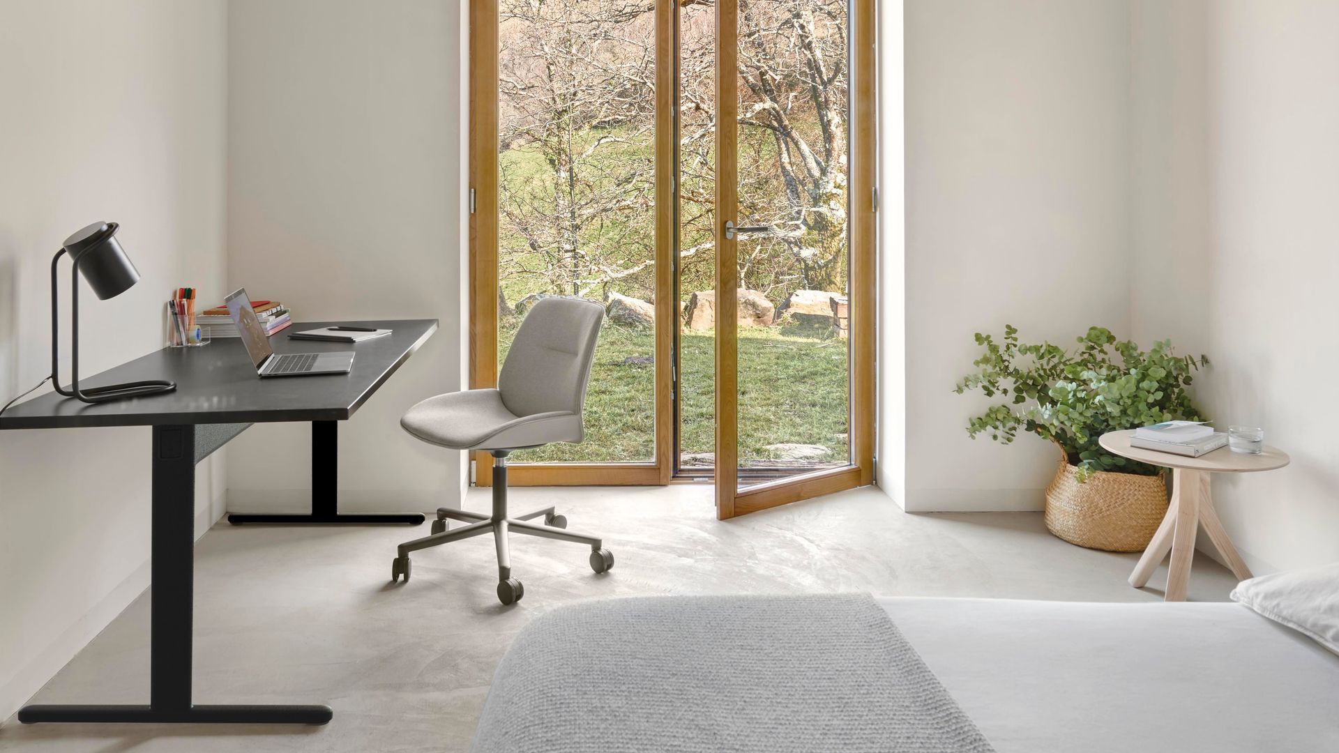 Dormitorio con salida al jardín, puerta de madera y cristal, escritorio negro y silla con ruedas gris
