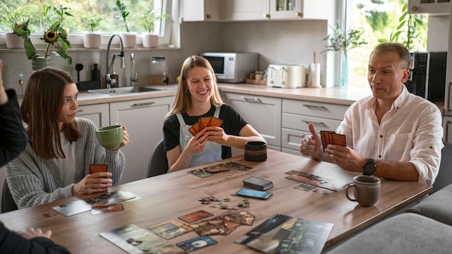 Familia jugando a un juego de mesa en la mesa del salón
