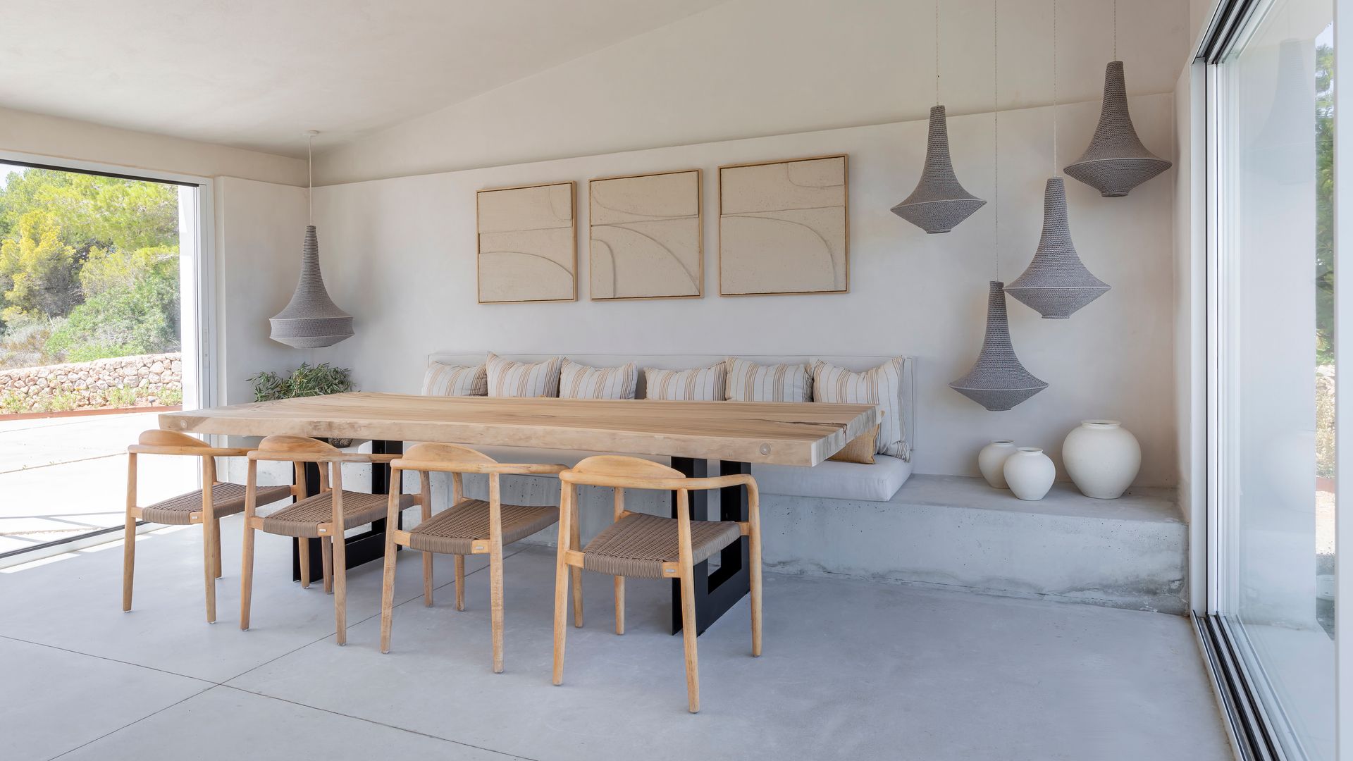 Comedor de estilo mediterráneo con salida al jardín, mesa de madera, banco de obra, adornos techo, sillas de enea