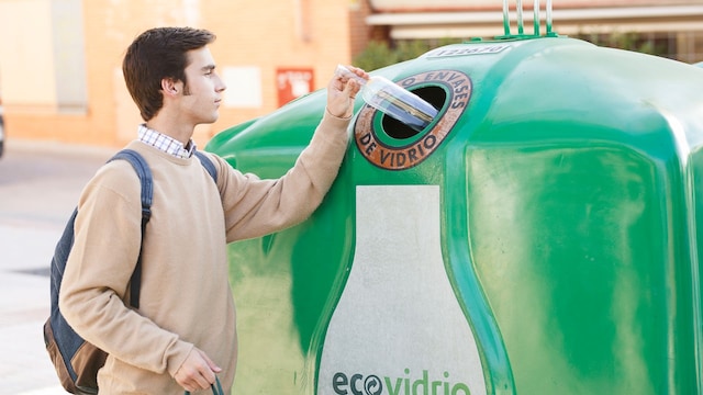 Hombre tirando una botella en un contenedor