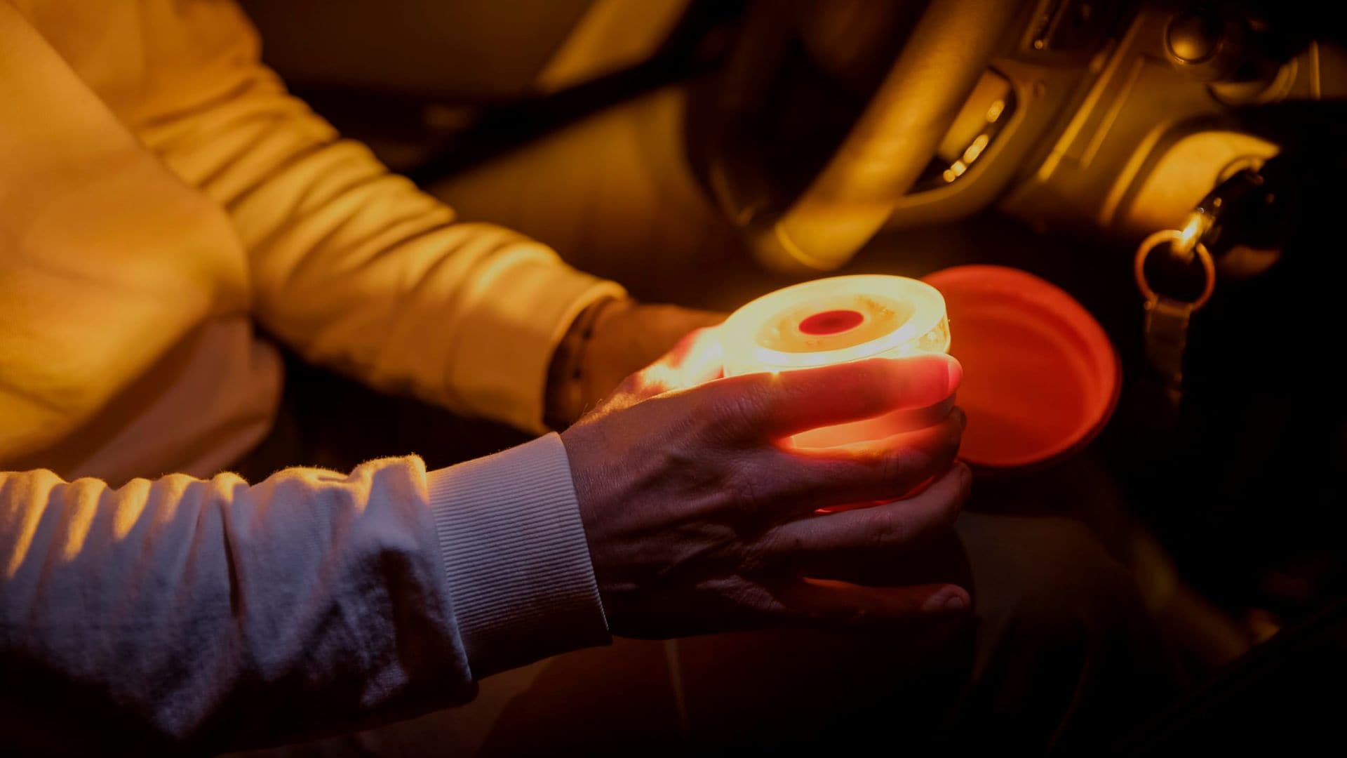 Hombre sacando la baliza V16 iluminada dentro de su coche