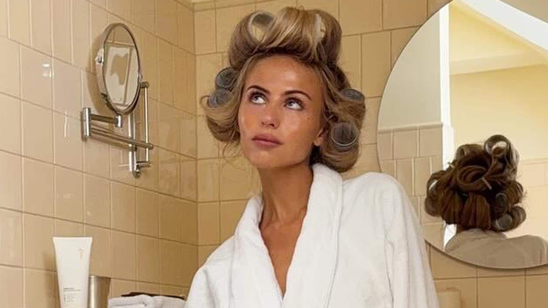 Elin Warn con albornoz blanco y rulos en un baño