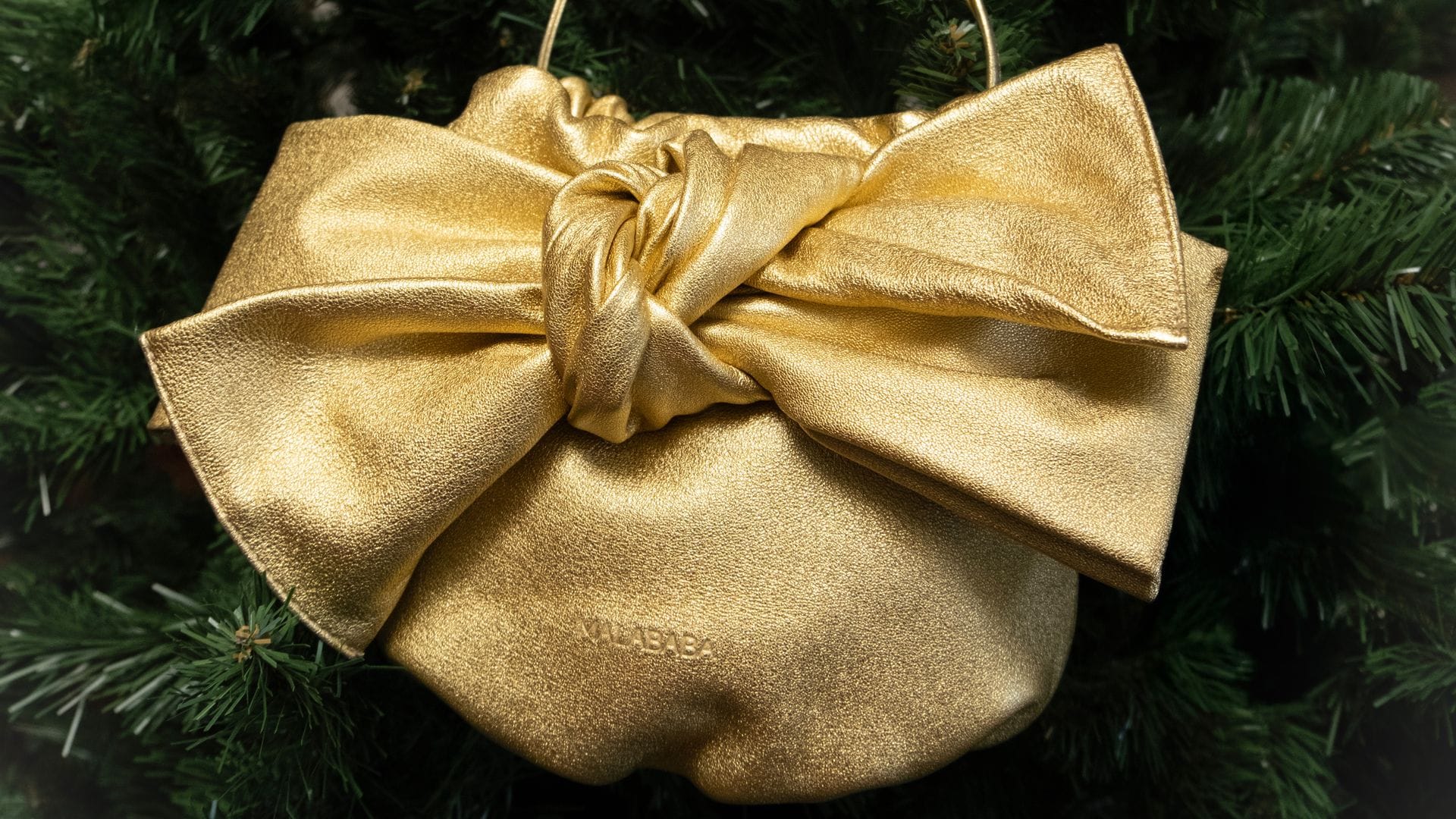 Bolso dorado con lazo de Malababa colgado en el árbol de Navidad