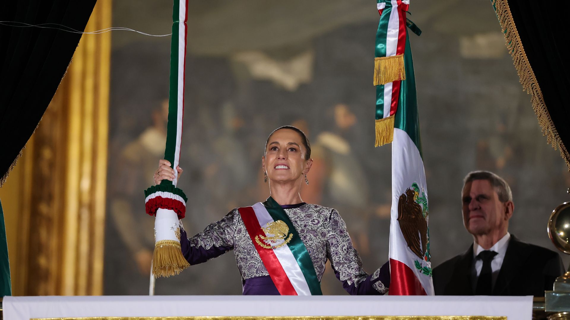 Claudia Sheinbaum en el balcón principal de Palacio Nacional acompañada del primer caballero, su esposo José María Tarriba.