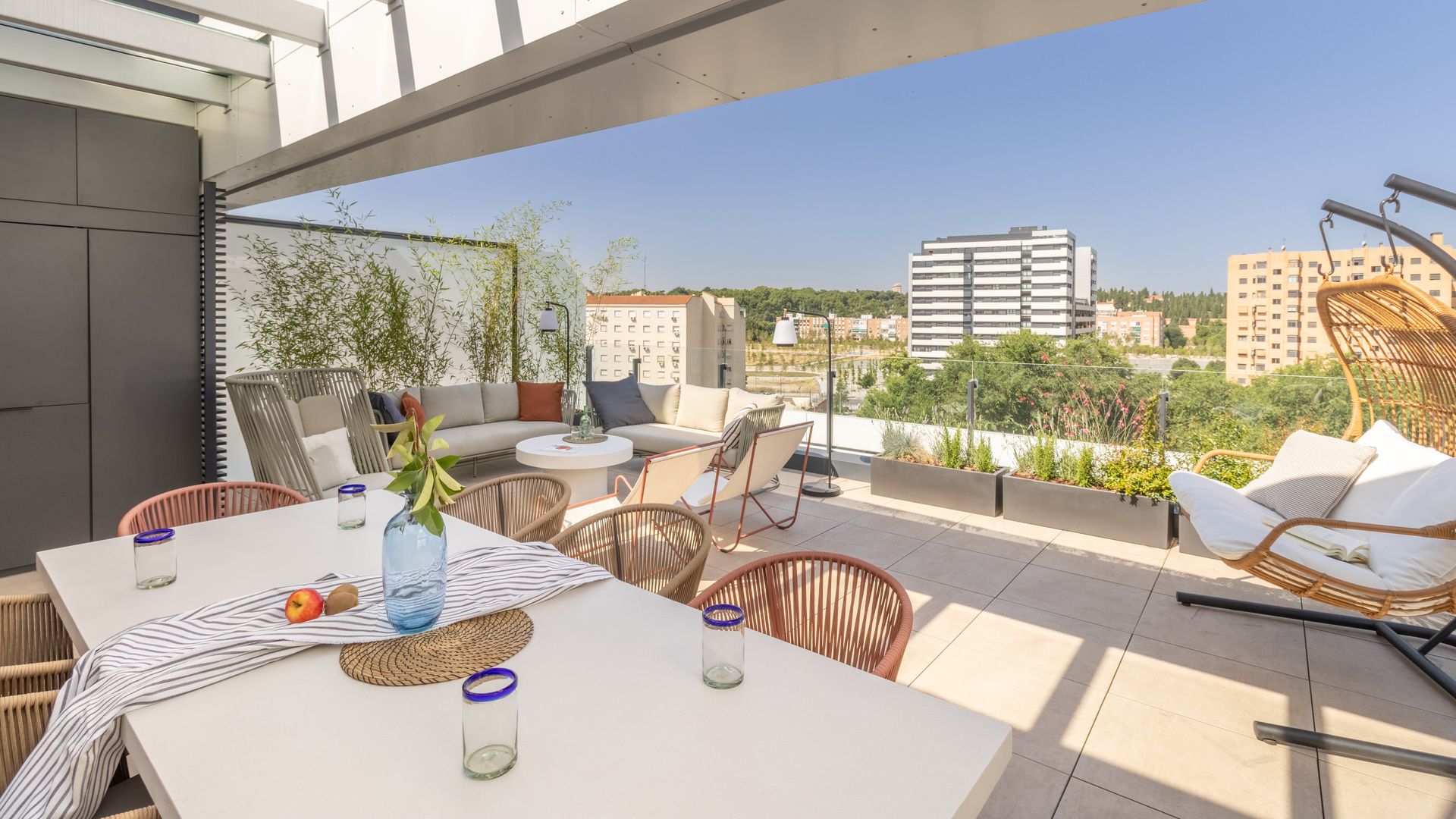 Terraza con pérgola y zona de comedor, estar y relax, jardineras y barandilla de cristal 