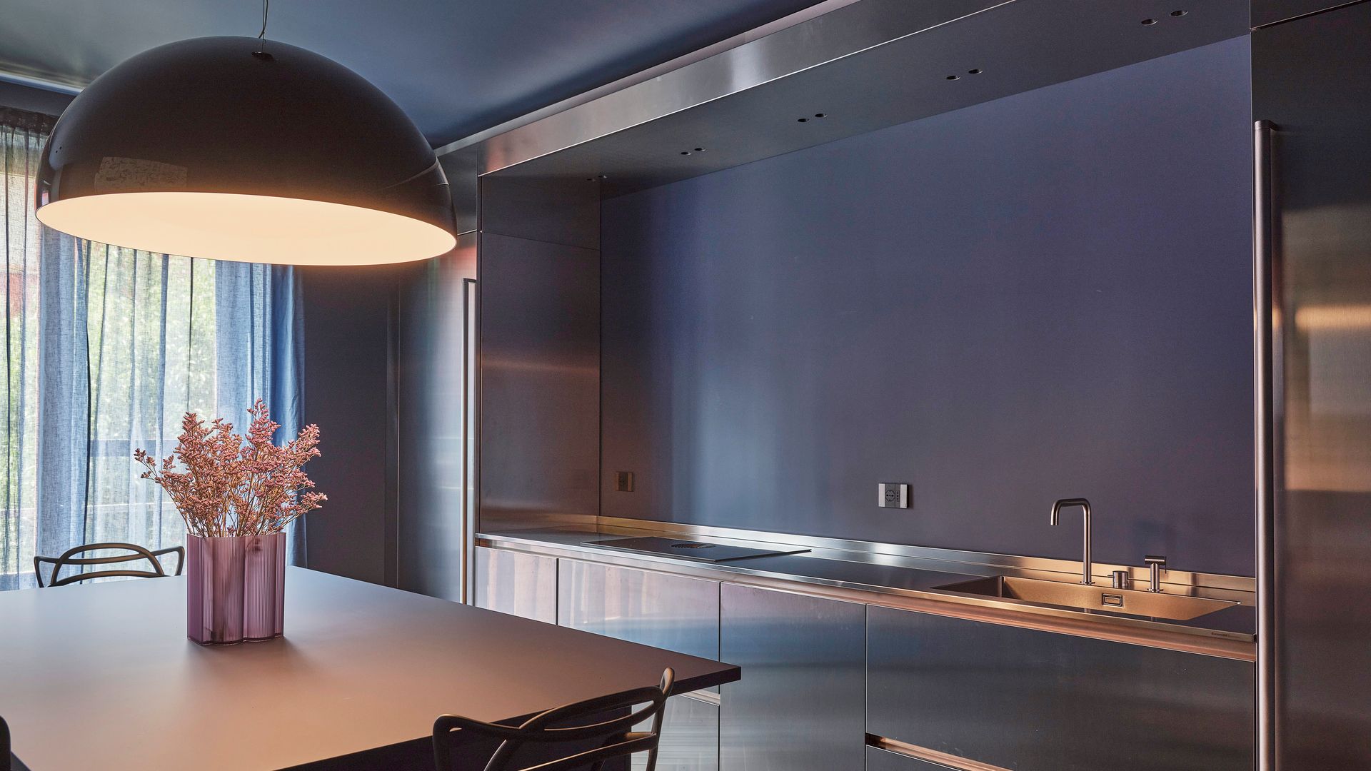 Cocina con paredes en azul grisáceo, comedor, lámpara de techo, suelo de madera
