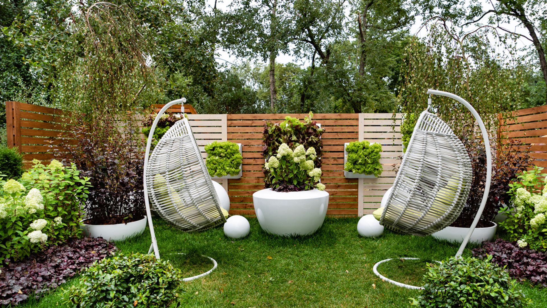 Heucheras y otras plantas en un bello jardín doméstico con balancines