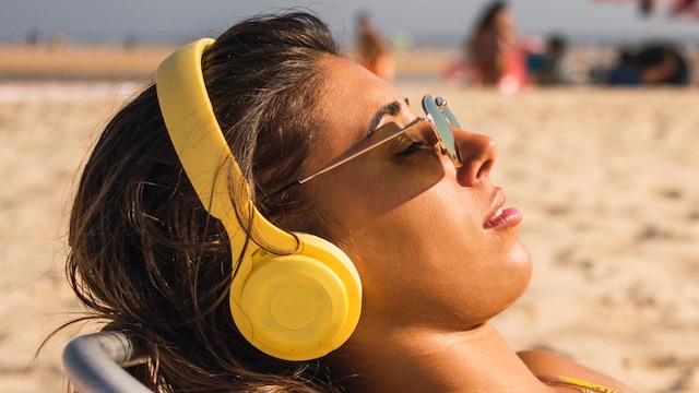 Una chica en la playa con auriculares de diadema 