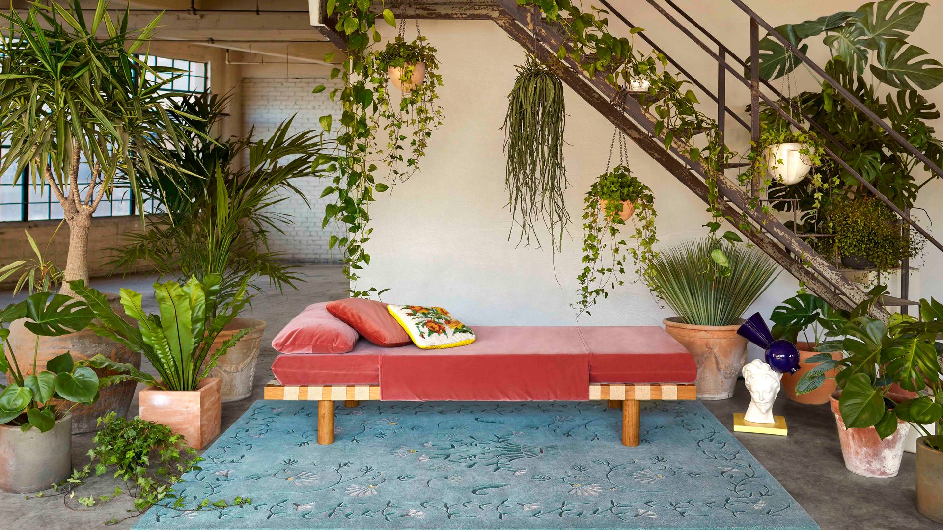Rincón con alfombra y chaise longue y plantas colgantes y macetas en el suelo