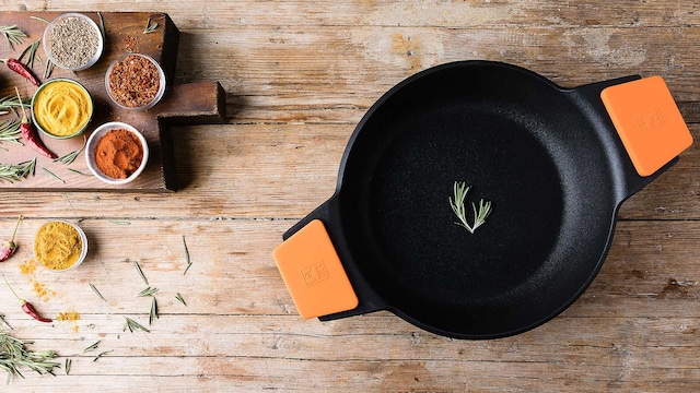 Olla o cazuela de BRA sobre una mesa de madera con múltiples especias y hierbas aromáticas.
