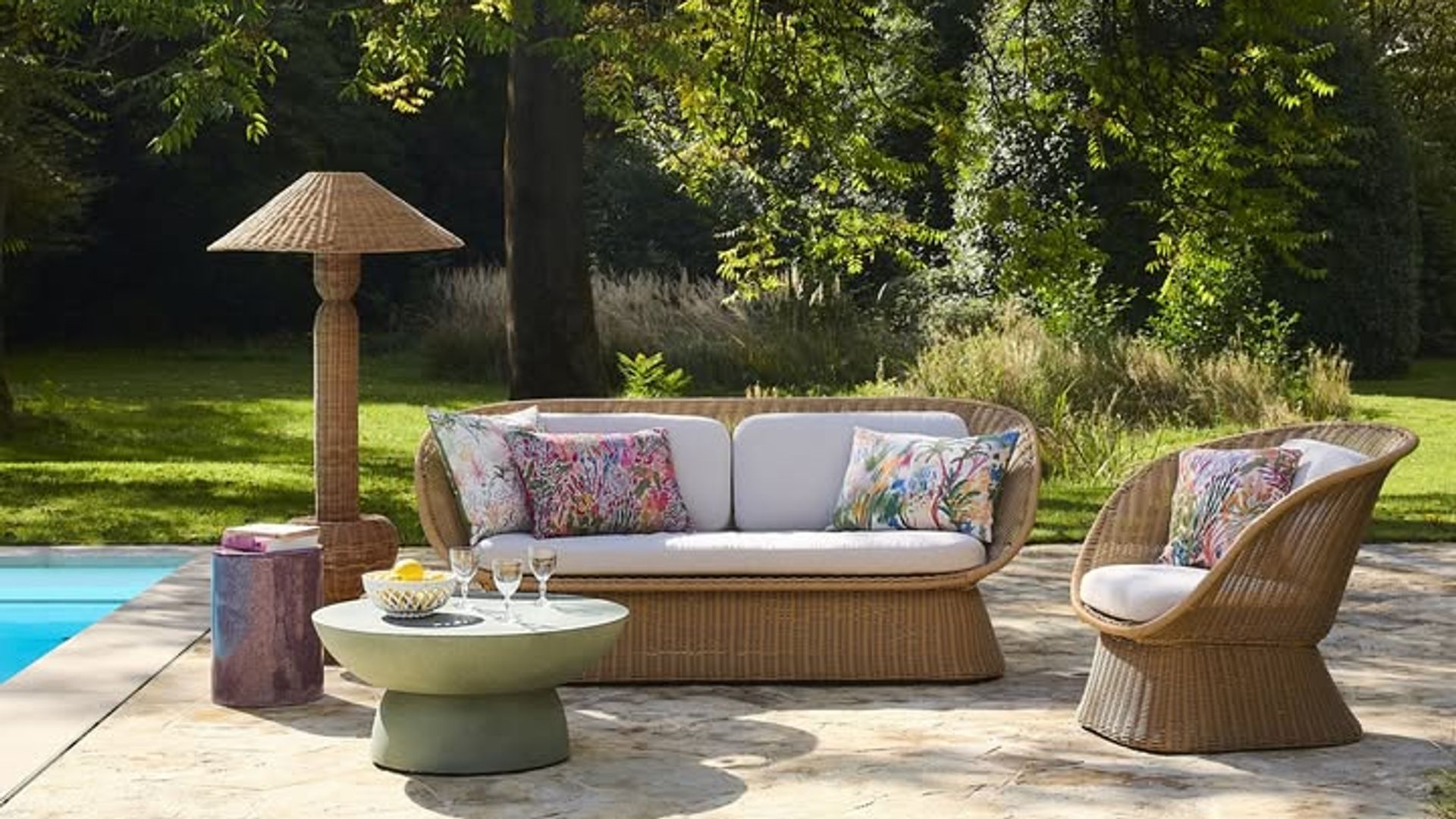 Colección primavera-verano 2026 de Maisons du Monde con mobiliario exterior junto a una piscina y un jardín.
