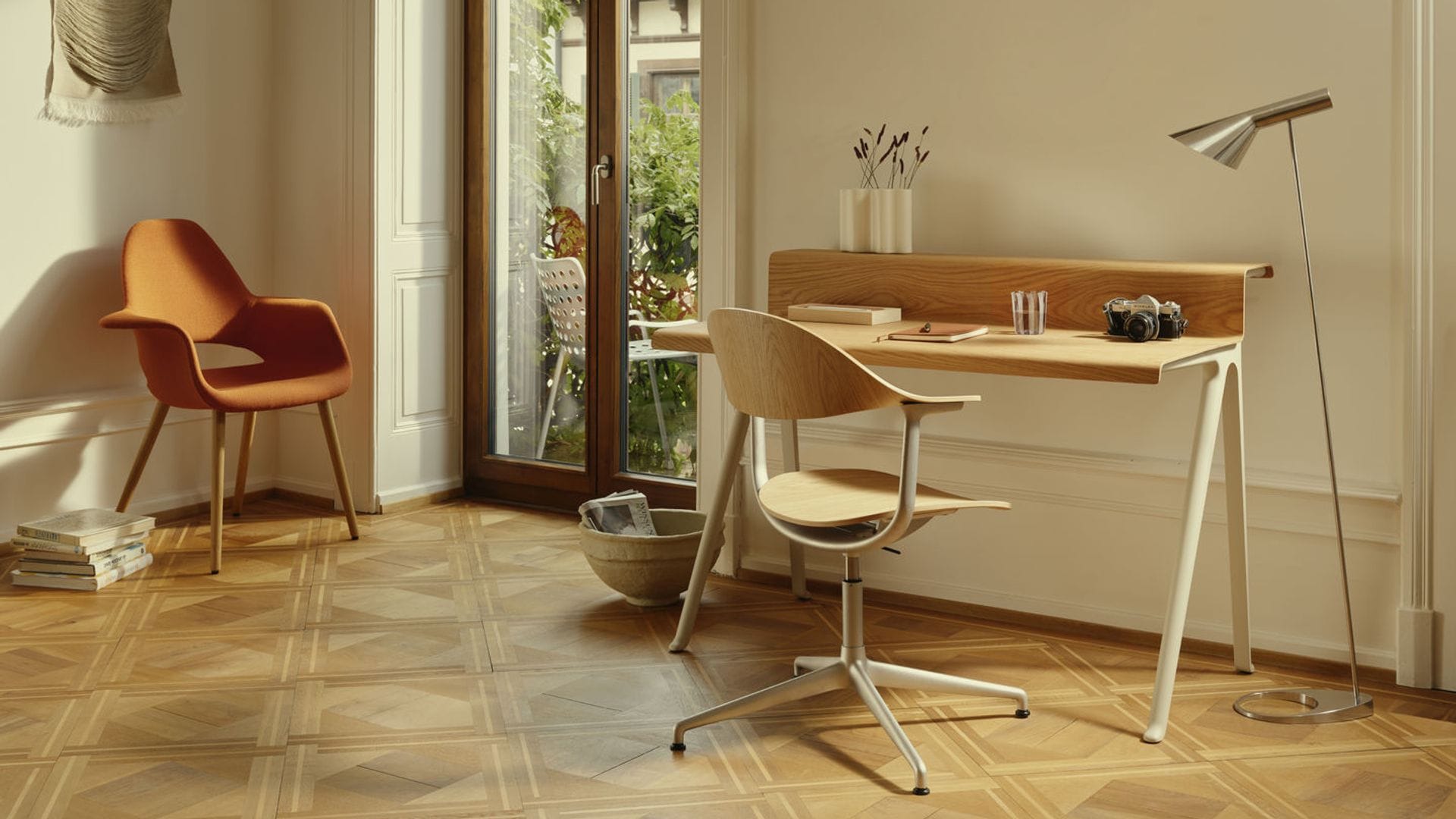 Despacho con escritorio de madera, silla de madera, silla tapizada junto a la ventana, lámpara de pie tipo flexo, suelo de madera