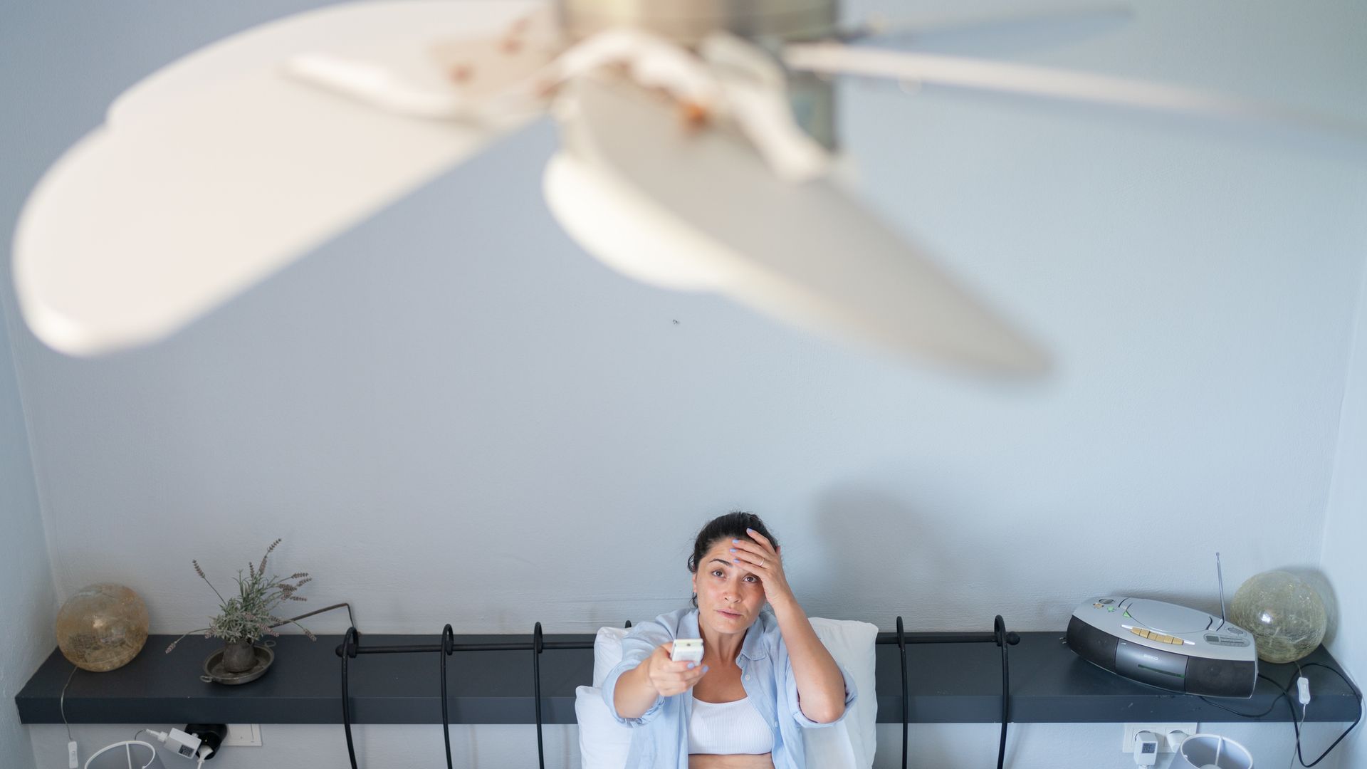 Mujer poniendo el ventilador de techo con mucho calor en casa.