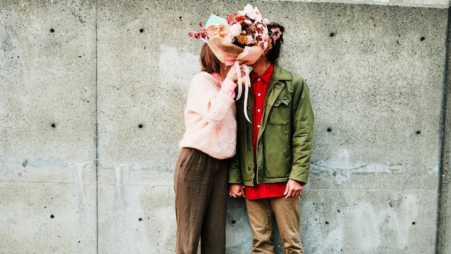 retrato de una pareja besándose detrás de un ramo de flores