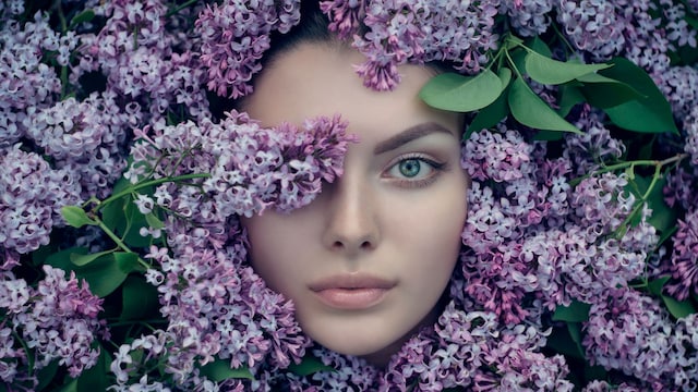 Mujer con ojos azules rodeada de flores