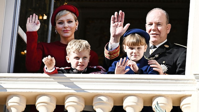 Plano medio de Charlene, Alberto, Jacques y Gabriella de Monaco saludando desde un balcón real en un evento
