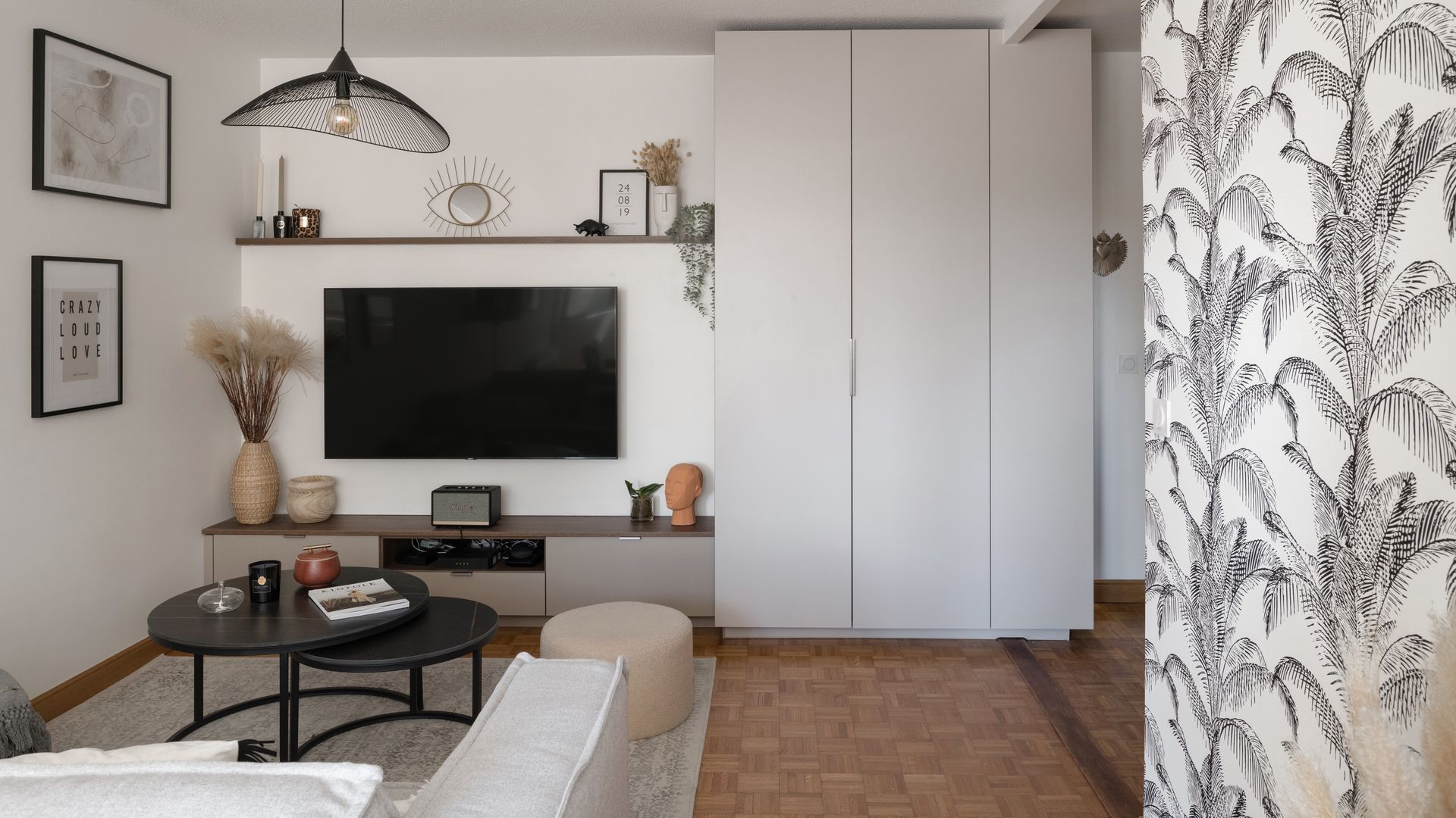 Salón con televisión en la pared, armario gris hasta el techo, mueble bajo, lámpara de techo, mesas de centro negras