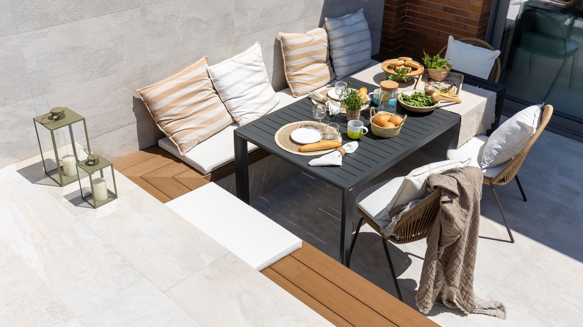 Terraza con banco de obra, cojines, mesa de comedor metálica negra