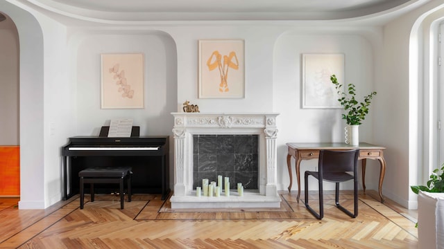 Salón con chimenea, piano a un lado, consola al otro, molduras en el techo, y la pared, suelo de madera en espiga