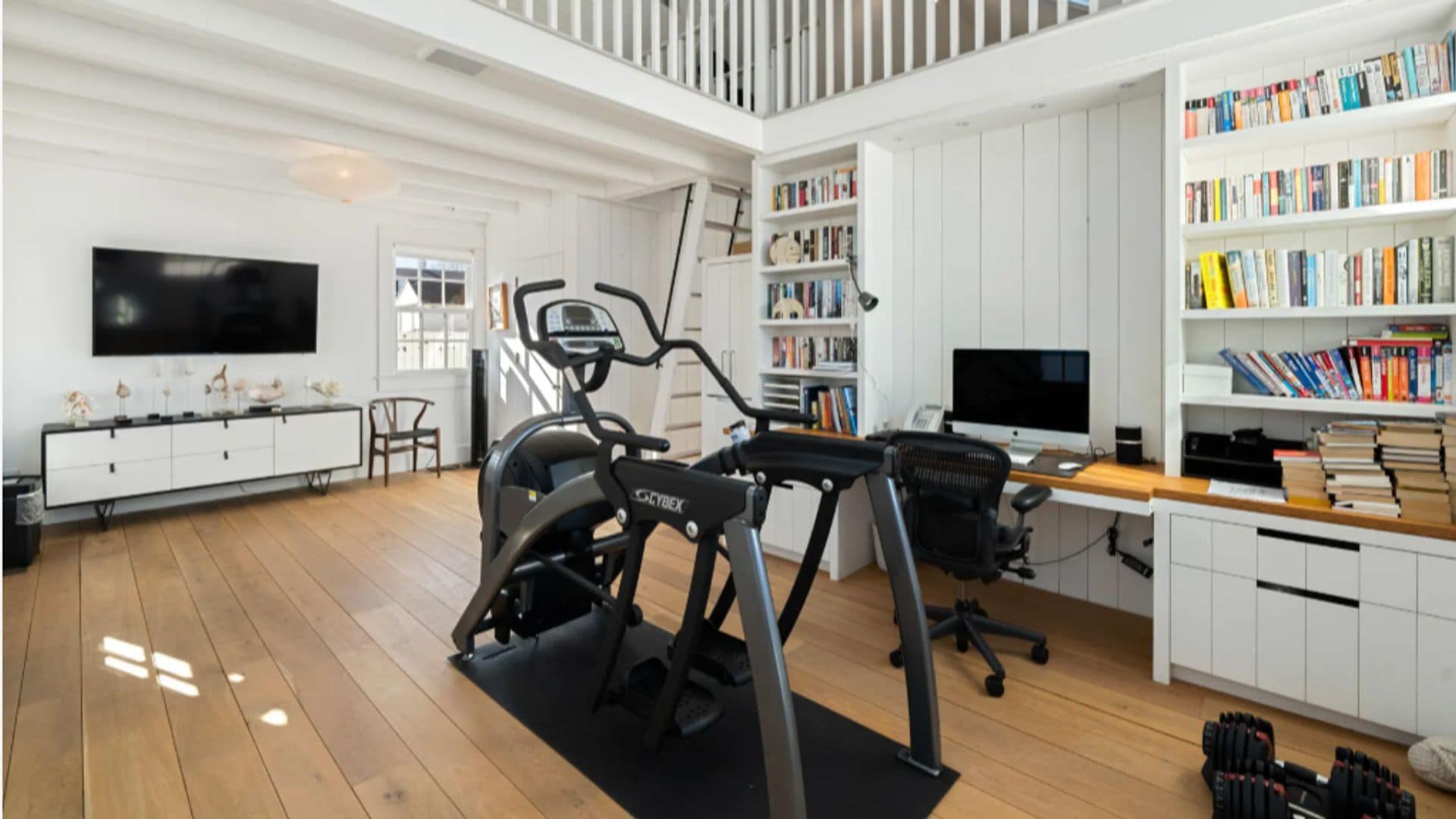 Despacho mansión Taylor Swift con máquina de entrenamiento, librería, zona de escritorio, mueble de televisión