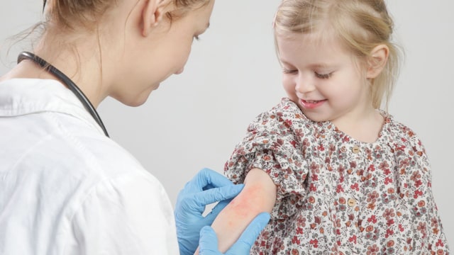 Dermatóloga observa erupción en la piel de una niña