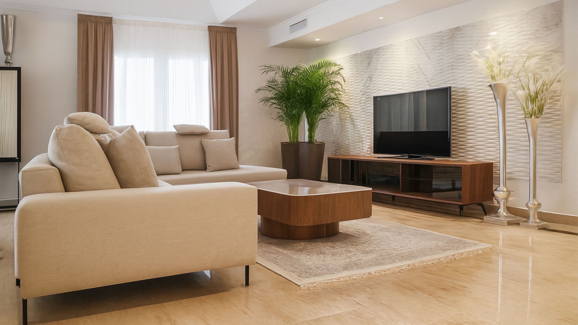 Salón con falso techo, iluminación perimetral, suelo de mármol, sofá beige, mueble de televisión, plantas en maceta, cortinas, visillos blancos, mesa de centro