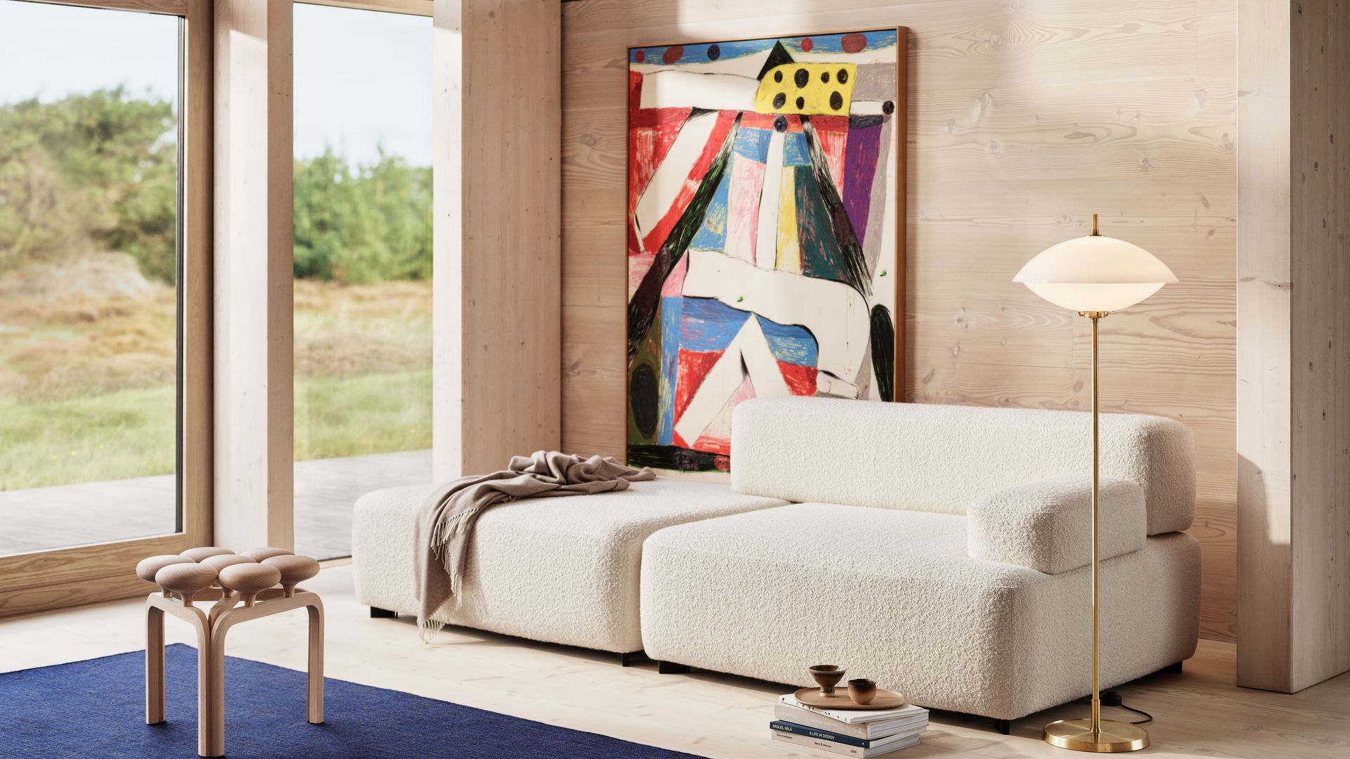 Salón con sofá blanco, cuadro de colores en la pared del sofá, alfombra azul y lámpara de pie dorada 