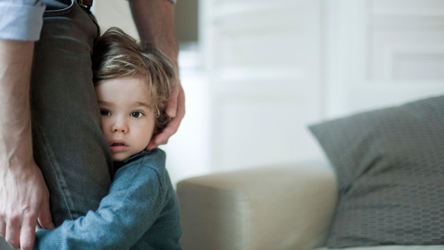 Niño tímido cogido a la pierna de su padre