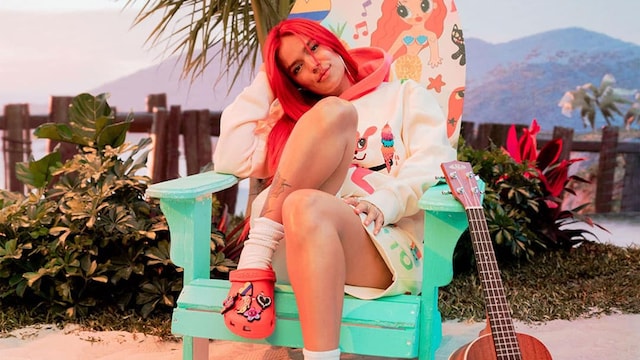 Karol G con zuecos crocs en color rojo