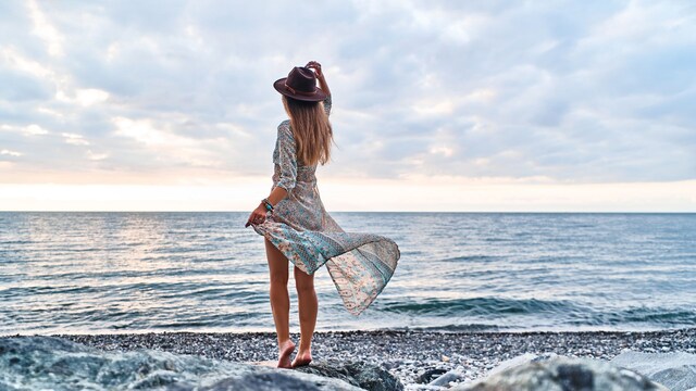 mujer relajada en la playa, descalza junto al mar