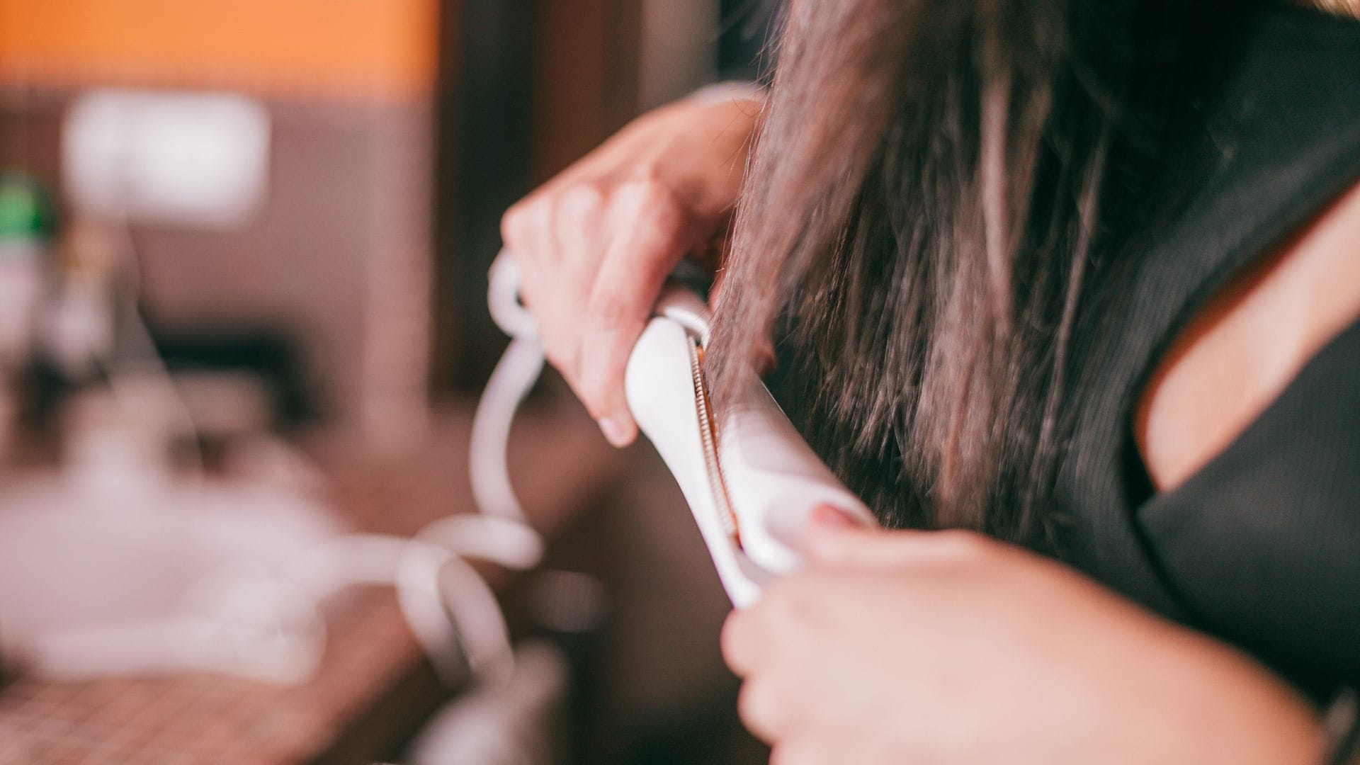 Mujer utilizando una plancha para el cabello en plano detalle.