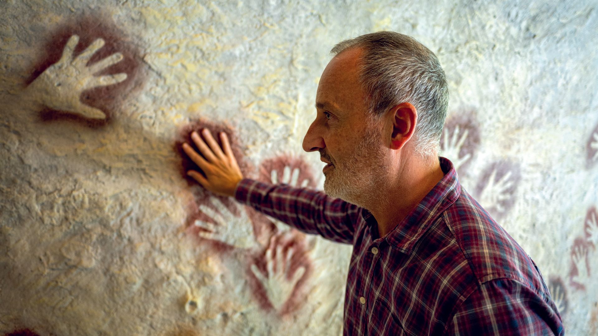 Eduardo Palacio-Pérez muestra el panel con las manos en negativo de la cueva El Castillo de Puente Viesgo.