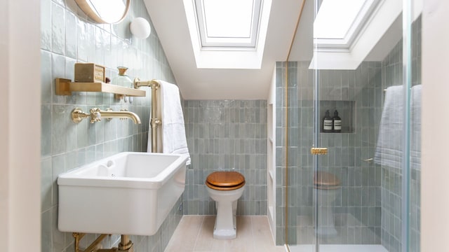 Baño abuhardillado con paredes azulejos en azul claro, ventanas de techo, ducha y grifería dorada