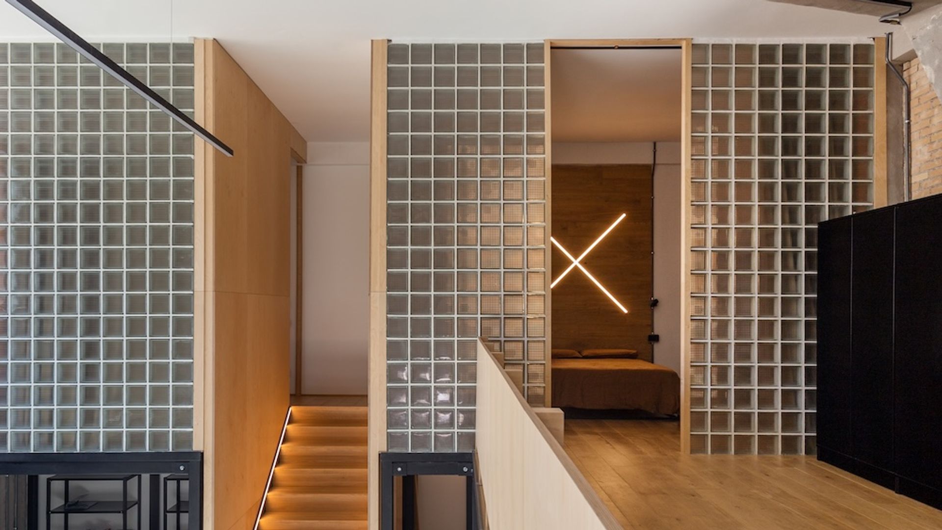 Interior casa en dos alturas con tabique de pavés y escalera de madera sin barandillas