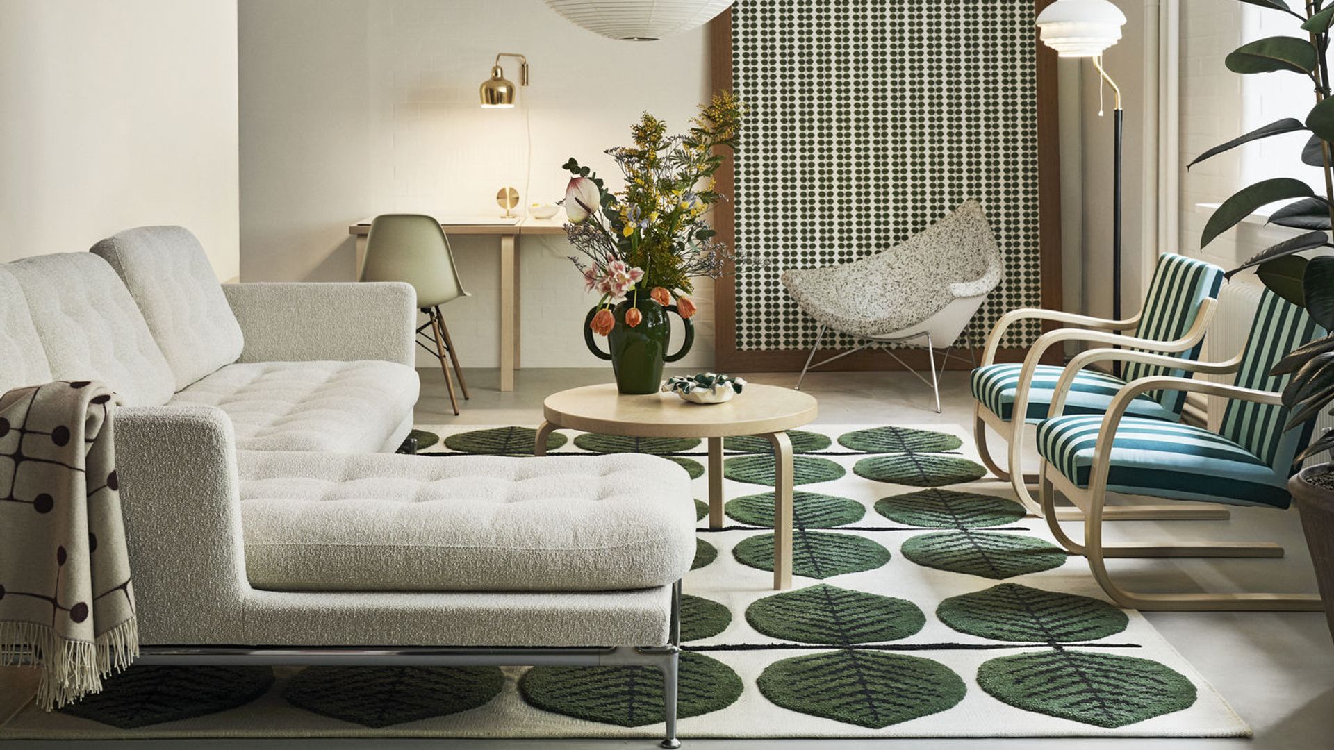 Salón con sofá blanco, lámpara de papel, alfombra, mesa de centro de madera, sillas con tapicería de rayas verdes y blancas
