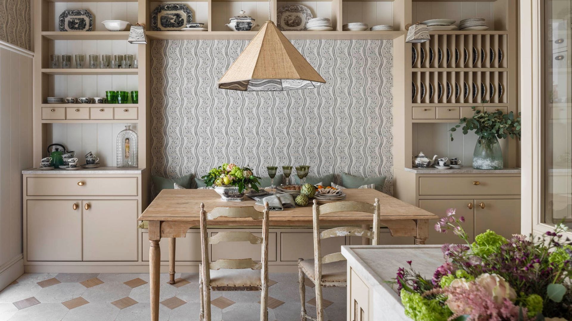 Cocina con comedor, mueble a medida de estilo rústico con platero, armarios, baldas y calorcitos, sillas de enea, suelo de cerámico, vigas y lámpara de techo 